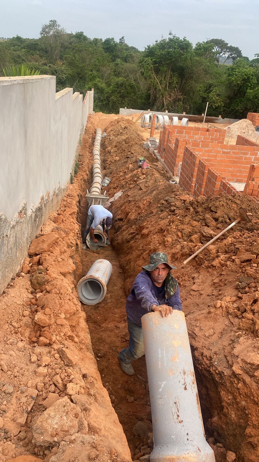 tubo de concreto sendo instalado em obra residencial para drenagem de aguas pluviais